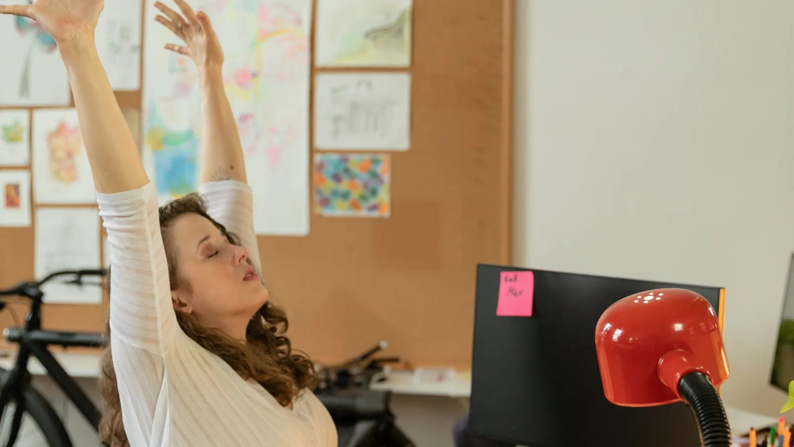 Person stretching arms overhead at their desk during a work break