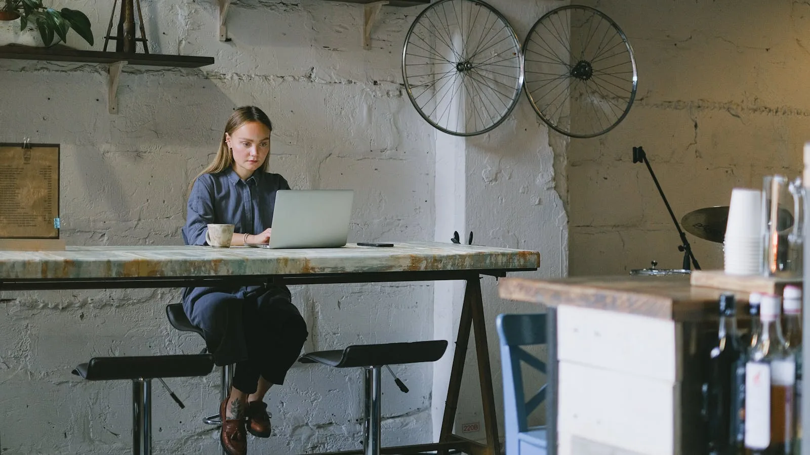 Woman working on a laptop at a bar table in a cafe