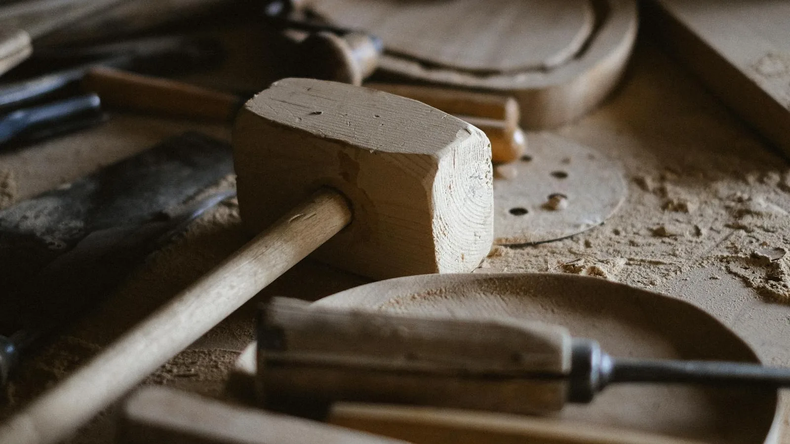 Wooden mallet and hand tools on a workshop bench, sawdust scattered around