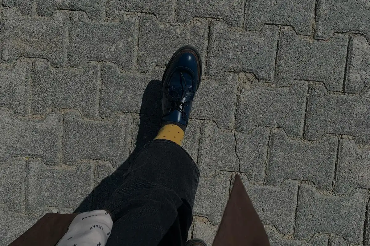 Legs and feet walking along a paved sidewalk