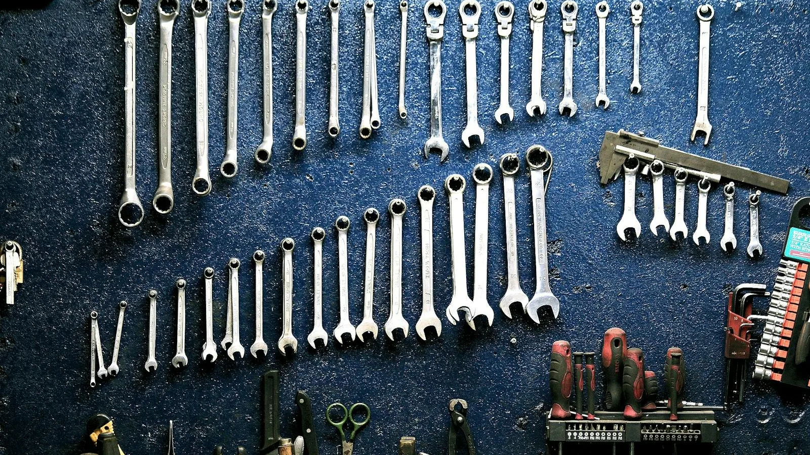 A pegboard wall organized with rows of wrenches, ratchets, and hand tools