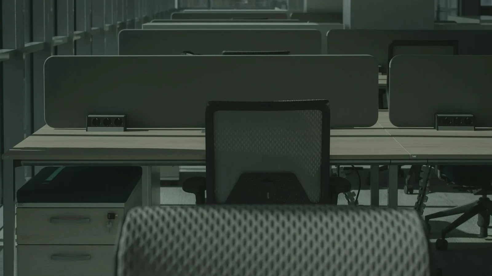 A modern open-plan office with rows of desks and ergonomic chairs at dawn