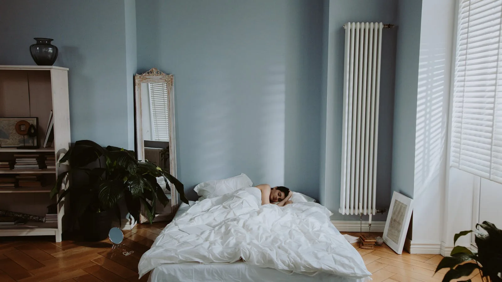 Person sleeping on their side under a white duvet in a quiet bedroom