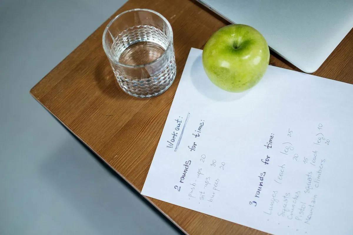 An apple and dumbbells on a desk next to a measuring tape