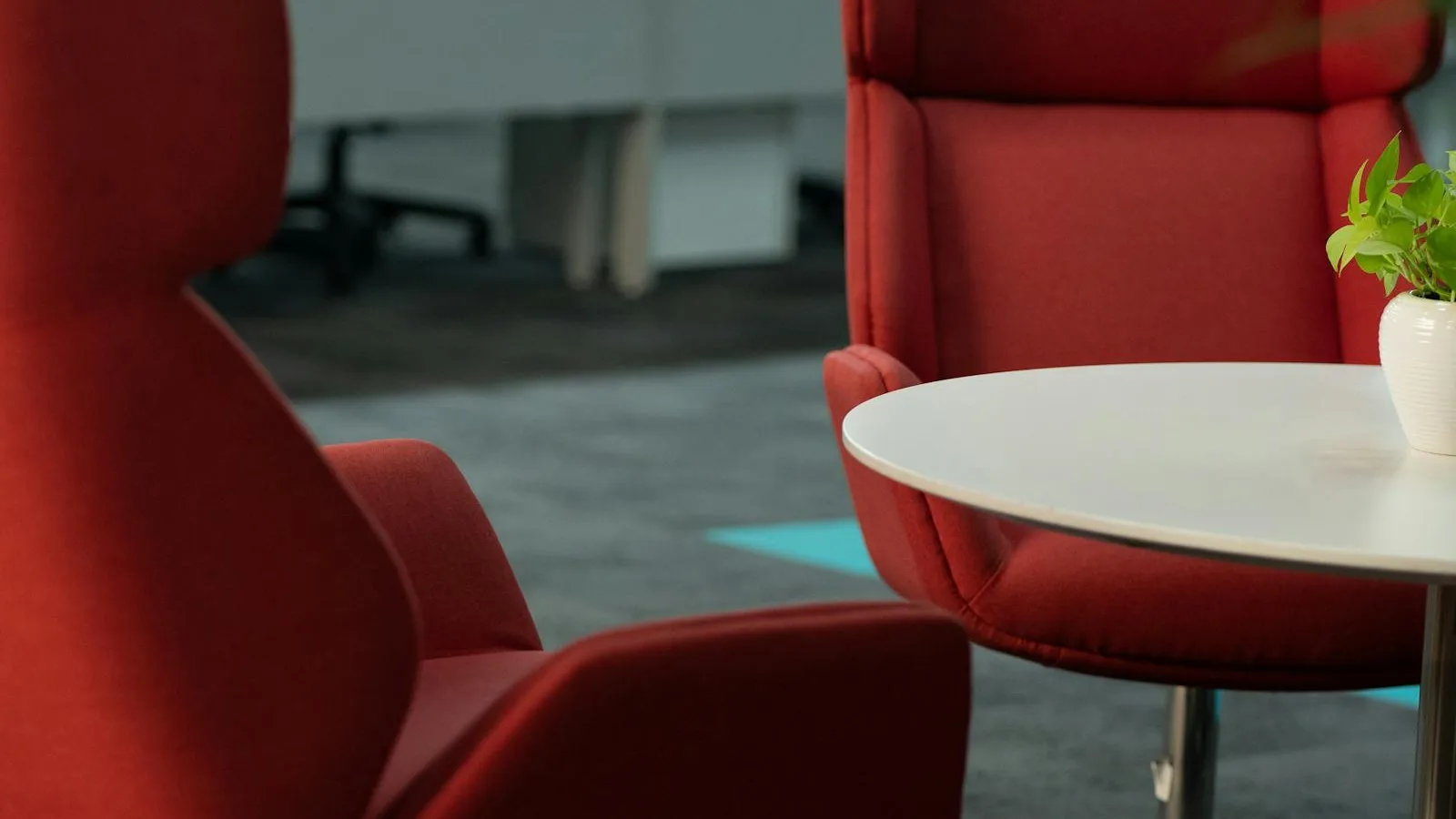 Two large red lounge chairs facing each other across a small white table in an office
