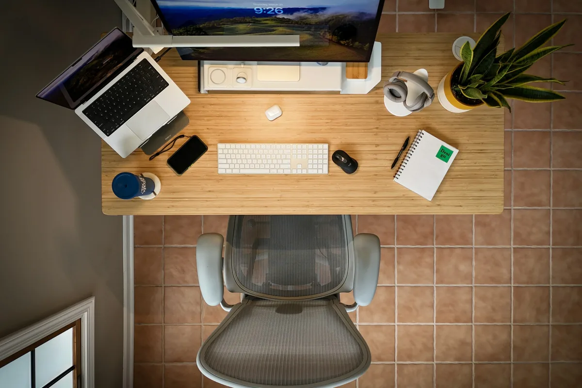 Overhead view of a standing desk with monitor, keyboard, and accessories competing for surface space