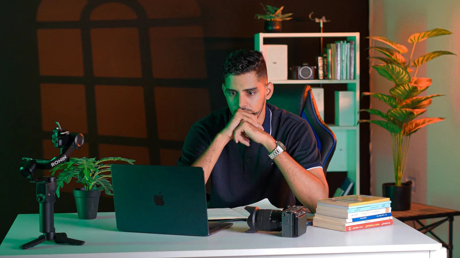 A person at a clean desk thoughtfully looking at a laptop
