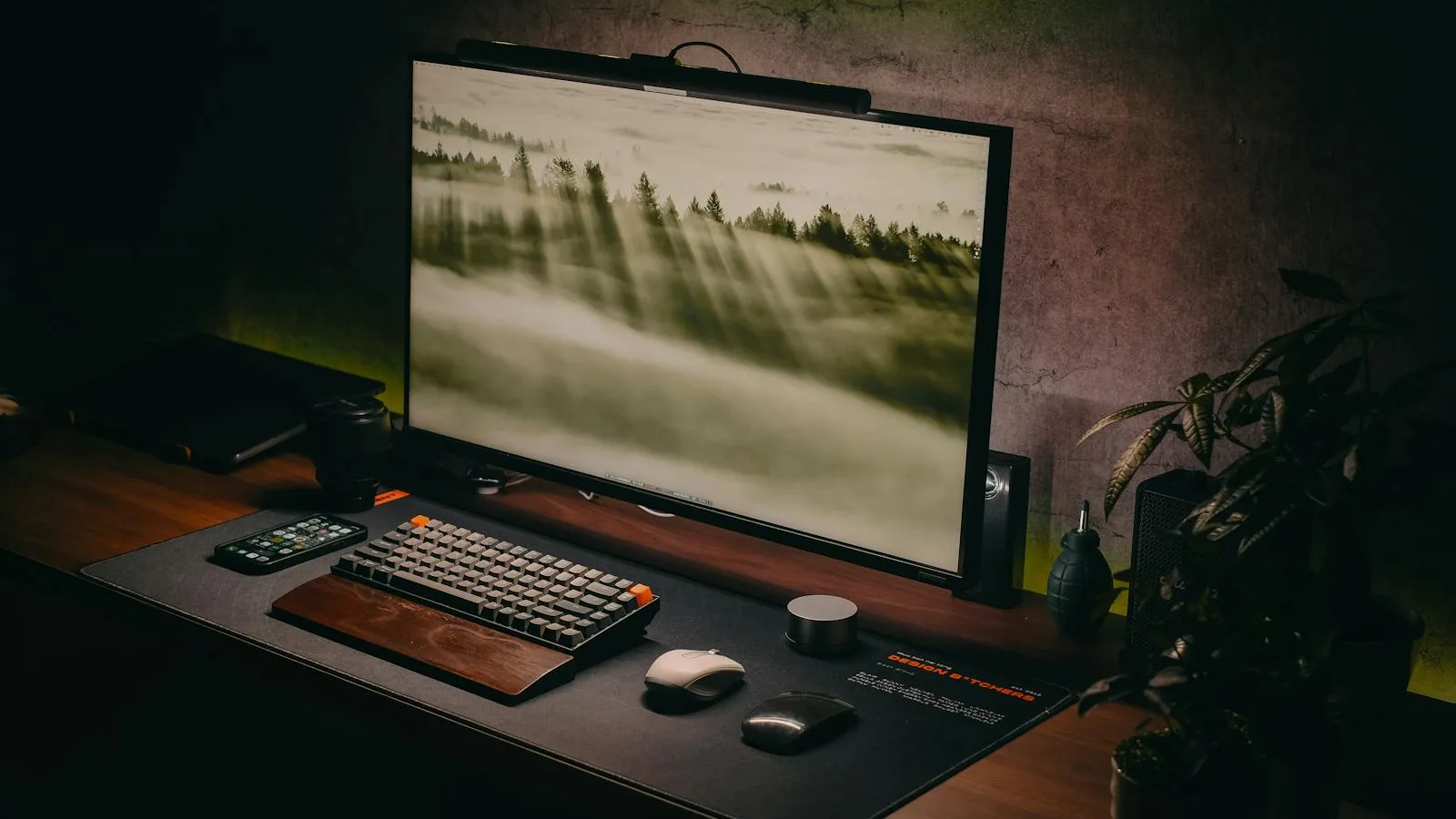 Tidy walnut desk with a large monitor, mechanical keyboard, and small plants